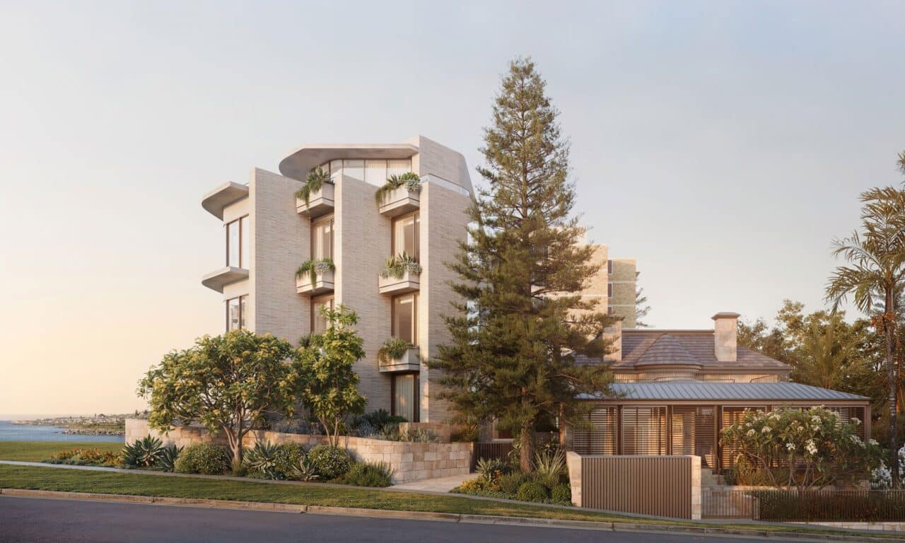 The modern multi-story Ballamac House, with its large windows and surrounded by lush trees and plants, stands proudly near a tranquil body of water under the clear sky in NSW.